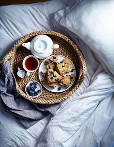 a wicker tray topped with cookies and blueberries next to a cup of tea