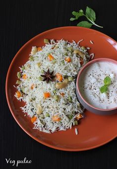 a plate topped with rice and vegetables next to a bowl of yogurt sauce