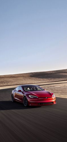 a red sports car driving on a road in the middle of an open desert area