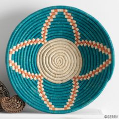 a blue and orange basket sitting on top of a white shelf next to a vase