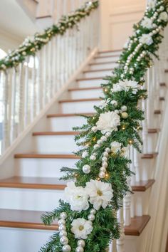 christmas garland with white flowers and greenery on the bannister, along stairs