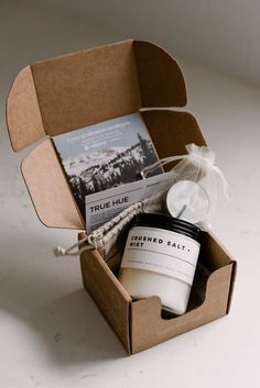 an open box containing a candle, soap and some other items on a white surface