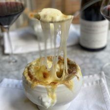 a white bowl filled with food sitting on top of a table next to two wine glasses