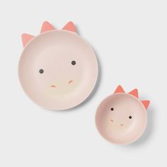 two pink plates with cats on them, one is empty and the other has an orange nose