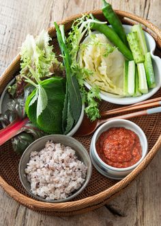 a basket filled with different types of food on top of a wooden table next to chopsticks