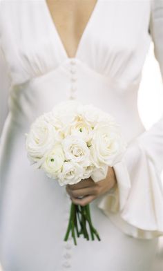 a bride holding a bouquet of white roses