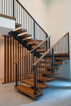 a wooden stair case with metal handrails in an empty room next to a wall