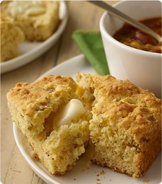 a close up of a muffin on a plate with a cup of soup in the background