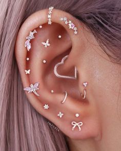 a woman with pink hair and ear piercings on her left side is wearing an ear cuff