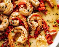 a white bowl filled with shrimp and cheese on top of a marble table next to bread