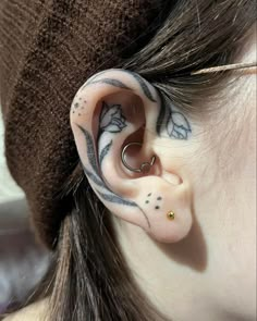 a woman with tattoos on her ear and behind the ear is a pair of piercings