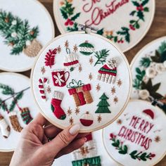 someone is holding up some christmas decorations on their embroidery hoops, which are decorated with red and green stocking