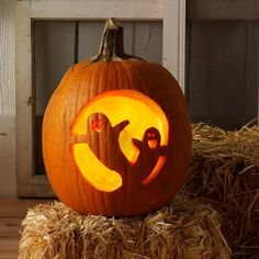 a carved pumpkin with an image of two birds on it sitting on hay bales