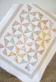 a quilted blanket sitting on the floor next to a white wall and brown carpet