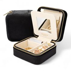 an open black case with jewelry in it on a white surface and the lid opened