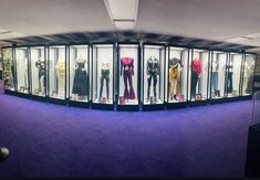 there are many mannequins in the glass cases on this purple carpeted room