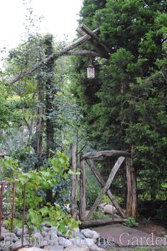 an old wooden gate in the middle of a garden with rocks and trees around it