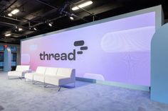 a room with couches and chairs in front of a large sign that reads threadd