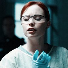 a woman with glasses and blue gloves holding something