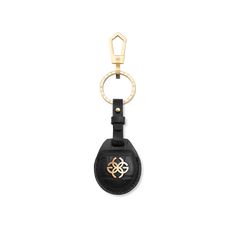 a black leather keychain with a gold logo on the front and back side