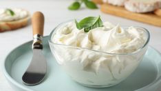 a glass bowl filled with whipped cream on top of a blue plate