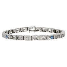 Era: Art Deco 1920s - 1930s Metal Content: 14k White Gold Stone Information: Synthetic Sapphires Carats: .50ctw Cut: Square Color: Blue Natural Diamond Carat: .02ct Cut: Old European Color: H Clarity: VS2 Total Carats: .52ctw Bracelet Style: Link Fastening Type: Tab Box Clasp with Side Safety Clasp Features: Filigree & Milgrain Detailing Measurements: Length: 7" Width: 7/32" (4.8mm) Total Weight: 10.7 Grams Stamps: 14k Condition: Pre-Owned Condition Note: Professionally Cleaned and Polished Luxury Art Deco Engraved Bracelets, Luxury Art Deco Jubilee Bracelet, Art Deco Bracelet, White Gold Bracelet, Sapphire Bracelet, Gold Stone, Art Deco Diamond, Sapphire Diamond, Diamond Art