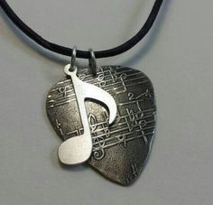 a guitar pick with a musical note on it's back drop pendant is hanging from a black cord