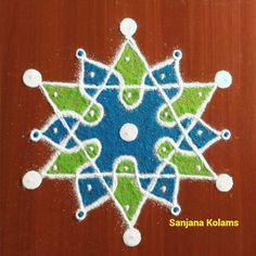 an intricately designed sand art on a wooden surface with the words sanja kolams written below it