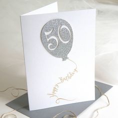 a white card with a silver balloon on it's side and the number sixty written in gold ink