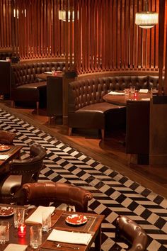 an empty restaurant with leather booths and checkered flooring on the walls, along with wooden slats