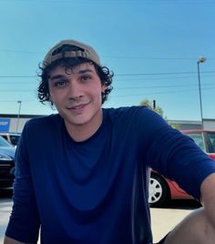 a young man sitting in front of a parking lot