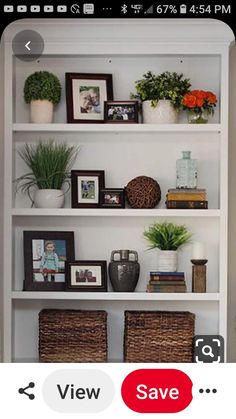 a white book shelf with pictures and plants on it, next to two wicker baskets