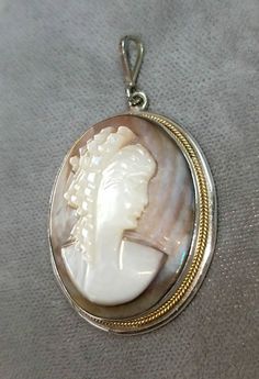 Hallmarked 800 silver Mother of Pearl cameo pendant. The cameo pendant measures approximately 1 1/2 inches x 1 inch. The necklace chain attached to the cameo pendant is sold separately. Other necklace styles are also available. The cameo pendant is in very good condition. The cameo pendant is circa 1940. The cameo pendant comes in a quality gift box. Silver Cameo Medallion Necklace, Silver Cameo Pendant Necklace, Silver Cameo Round Jewelry, Silver Cameo Round Pendant Jewelry, Silver Cameo Jewelry With Round Pendant, Round Silver Cameo Necklace, Collectible Cameo Jewelry With Round Pendant, Collectible Cameo Round Pendant Jewelry, Collectible Cameo Pendant Necklace