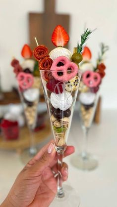 a person holding up a wine glass filled with desserts and pretzel toppings