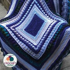 a crocheted blanket sitting on top of a wooden bench