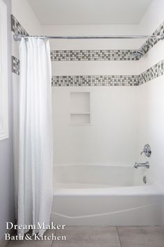 a white bath tub sitting next to a window in a bathroom with tile on the walls