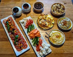 a table topped with lots of different types of food on plates next to bowls filled with dips