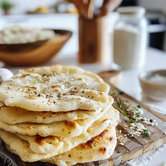 a stack of pita bread sitting on top of a wooden cutting board