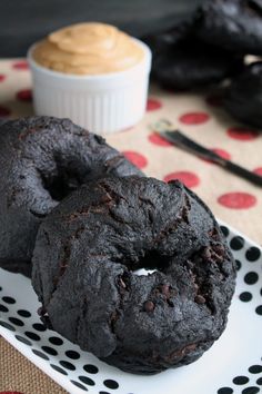 two chocolate doughnuts on a polka dot plate with peanut butter in the background