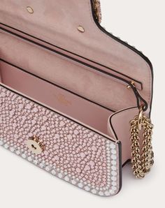 Valentino Garavani Locò small shoulder bag with rhinestone appliqué and Swarovski® covered VLogo Signature element. Equipped with both a detachable sliding chain strap and a detachable handle, this accessory can be worn as a crossbody/shoulder bag or carried as a handbag. - Magnetic closure - Removable leather handle - Removable sliding chain shoulder strap - Nappa leather lining. Interior: one slip pocket Shoulder strap drop length: min. 33 cm to max. 55 cm / min. 12.9 in. to max. 21.6 in. - Di Luxury Rose Gold Clutch Evening Bag, Luxury Bags With Rhinestones For Events, Luxury Shoulder Bag For Events, Luxury Rhinestone Event Bag, Luxury Embellished Event Bags, Luxury Rhinestone Event Bags, Luxury Embellished Clutch Shoulder Bag, Luxury Evening Bag With Rhinestones And Top Handle, Luxury Bedazzled Bags For Events