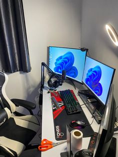 two computer monitors sitting on top of a desk next to a keyboard, mouse and headphones