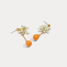 Orange Flower Stud Earrings are a fancy earring design among nature jewelry. They have enamel paint flowers and orange pendants, connected by 18k gold chain. These fruit and flower earrings come from Selenichast jewelry store. What's better than a combination of tangerine and gardenia? The fragrance of flowers, with the sour and sweet citrus, will bring you the feeling of crystal-like love. From the lustrous pearl in the little flower to the most shimmery sunshine yellow tangerine, this pair wil Gold Enamel Earrings With Flower Charm, Gold Earrings With Flower Charm In Enamel, Gold Earrings With Flower Charm And Enamel, Yellow Gold Enamel Dangle Earrings, Orange Dangle Pierced Jewelry, Enamel Drop Flower Earrings, Enamel Flower Earrings With Flower Charm, Enamel Dangle Single Earring, Enamel Flower Charm Earrings