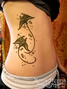 a woman's stomach with a tattoo design on the side of her body and an image of two dolphins