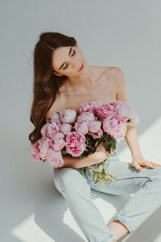 a woman sitting on the ground with flowers in her hands