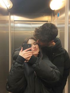 a man and woman taking a selfie in front of a bathroom mirror with their cell phone