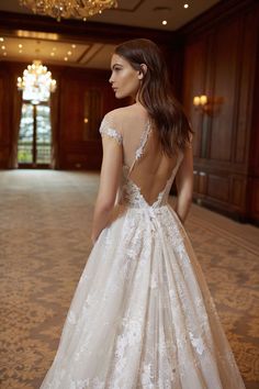 a woman in a wedding dress looking down at the floor with her back to the camera