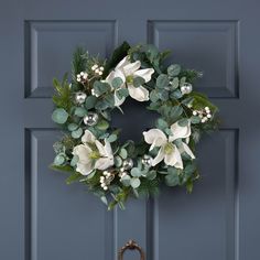 a wreath with white flowers and greenery hangs on the front door