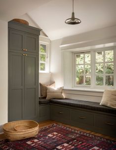 a room with a bench, window and rug on the floor