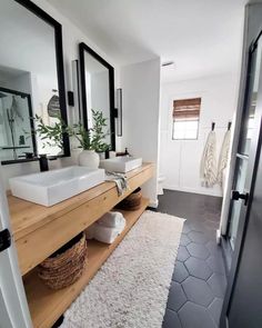 a bathroom with two sinks, mirrors and rugs on the floor in front of it