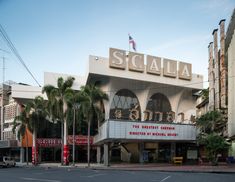 an old movie theater with palm trees in the foreground